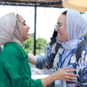 Two young women in hijabs facing each other and smiling
