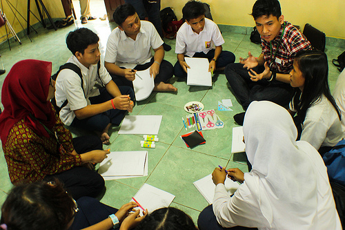 students sit on the ground in a circle talking