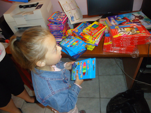a little girl holds a pack of markers