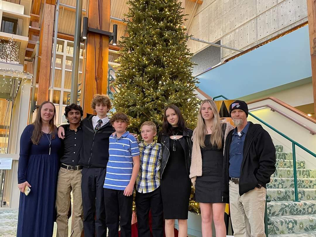 Host Family Posed In Front Of Christmas Tree With Exchange Student