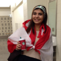 Roaa smiling and wrapped in the Lebanese flag and wearing a headband that reads Lebanon. 