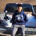 Ashfaque sitting in back of a truck with donations to Salvation Army around him. 