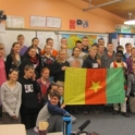 Nouredine and a group of students holding the Cameroonian flag in a classroom. 