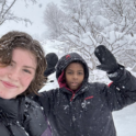 Alum Poses For Selfie With Another Person In The Snow Wearing Winter Coats And Gloves