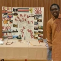 Benjamin near his International Education Week poster during a presentation