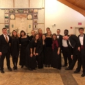 Rina and a large group of people wearing suits and ties and dresses smile