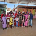 Alumni and participants pose together. Some are wearing party hats.