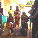 Women sit around a plastic bag and bucket after going to the market