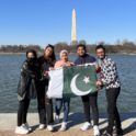 Five YES students from Pakistan stand in front of the Washington monument holding a Pakistani flag