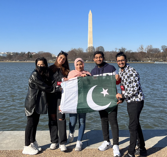 Five YES students from Pakistan stand in front of the Washington monument holding a Pakistani flag