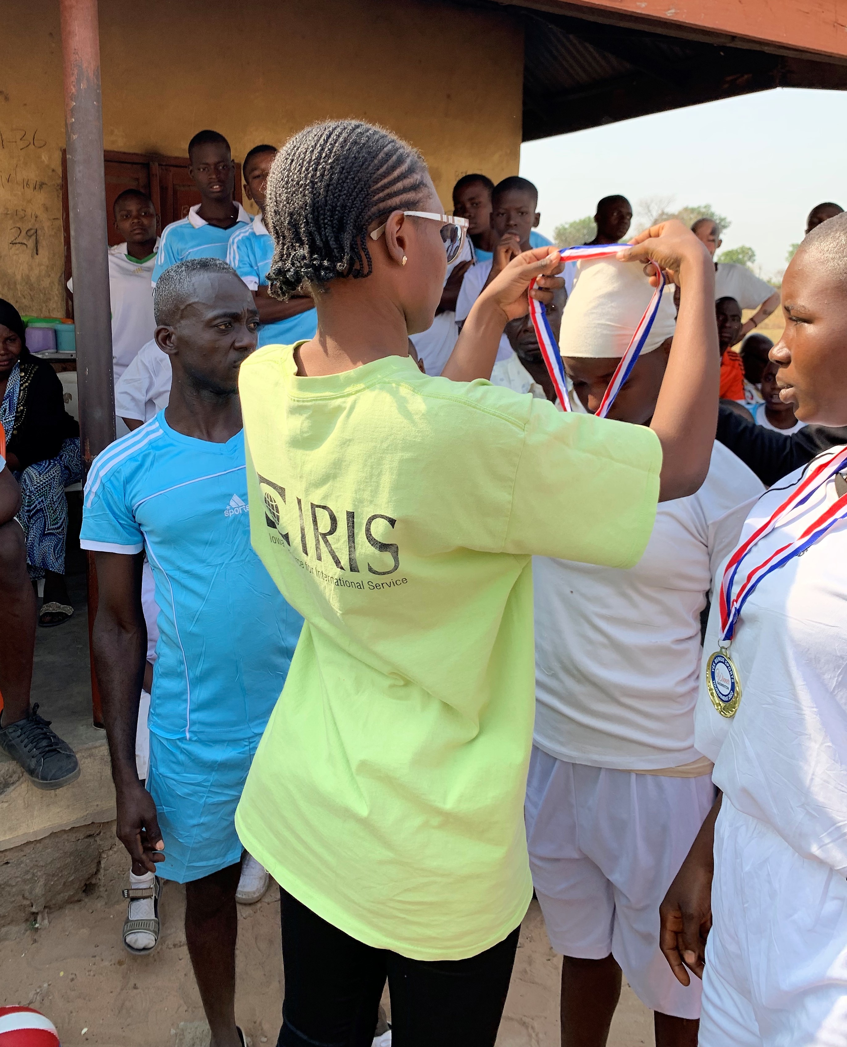 a YES alum wearing an IRIS tshirt puts medals around participants' necks