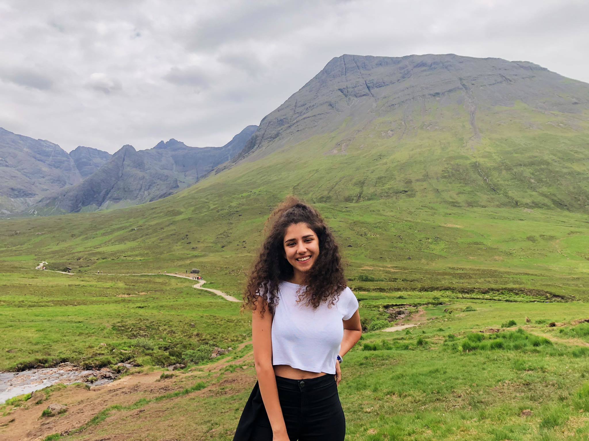 YES alumna, Natali, standing in front of green mountains.