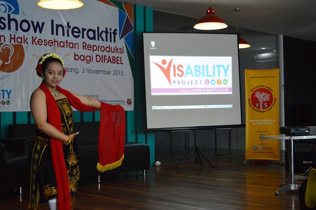 An alum stands in front of a screen that says visability