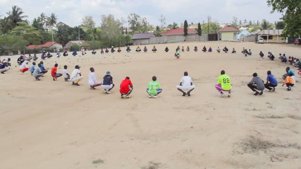 A group of students sitting in a big circle on a baseball field