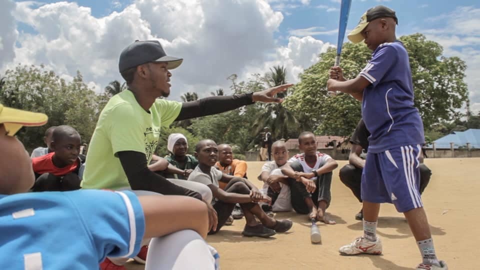 YES alum, Mussa, teaching a group of students baseball techniques.