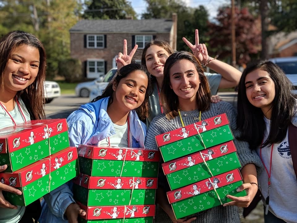 Group of young girls holding gifts and smiling together.