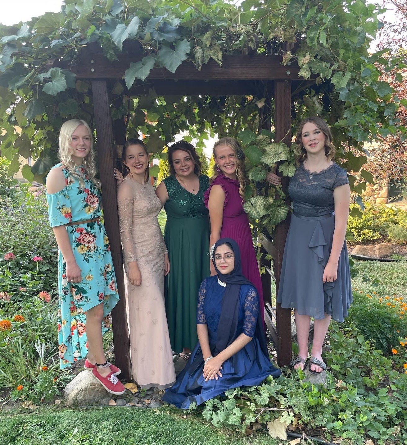 Mariam and her friends pose for a group photo outside near a green leafy background.  Jpeg 1