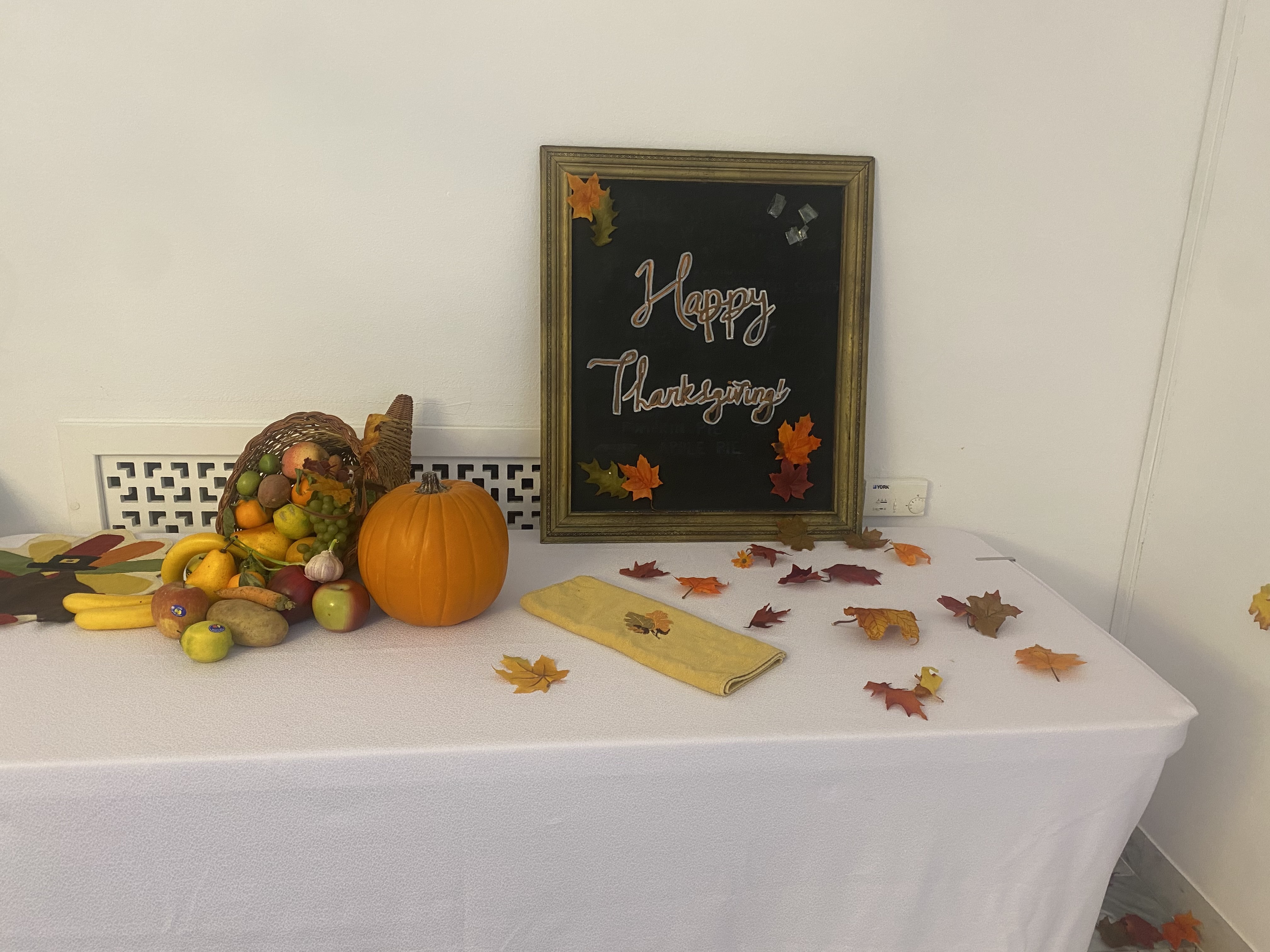 A Happy Thanksgiving sign on a table with decorative leaves and fruits