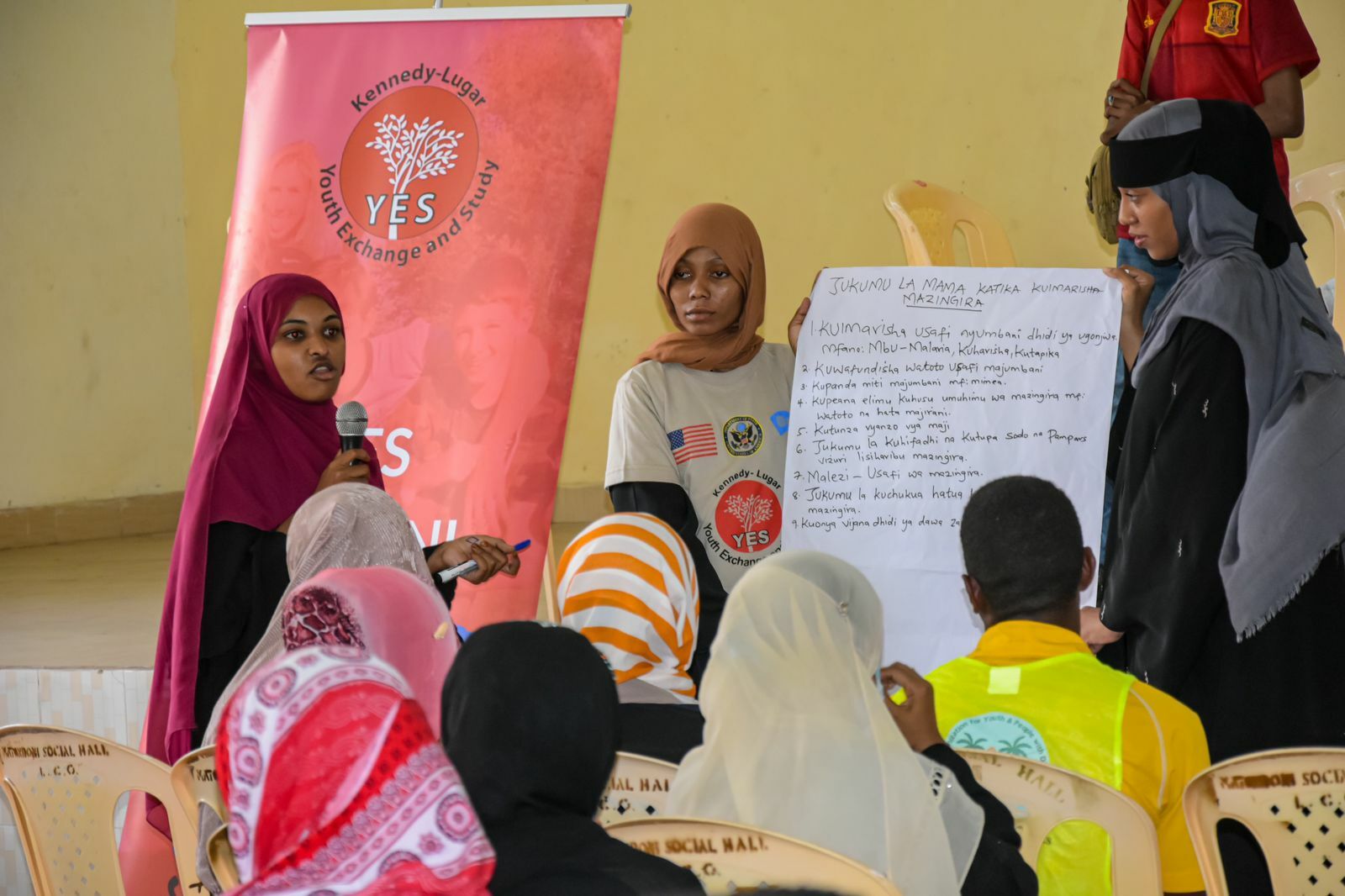 A group of participants giving a presentation holding a poster