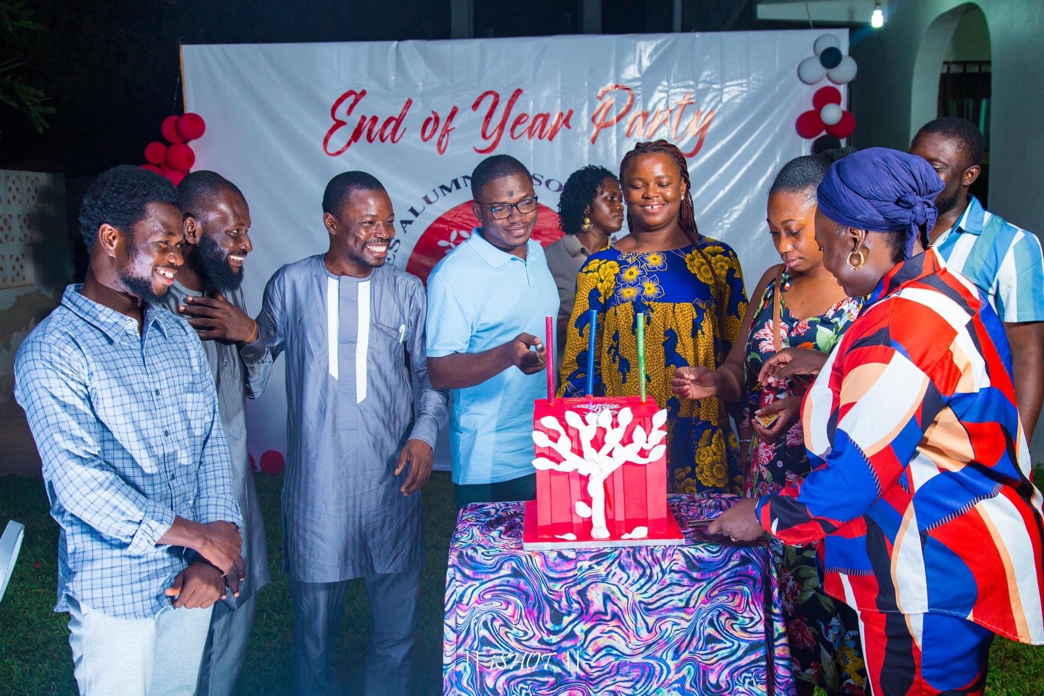 A Group Of People Smiling And Lighting Candles In Front A A Banner That Reads End Of Year Party