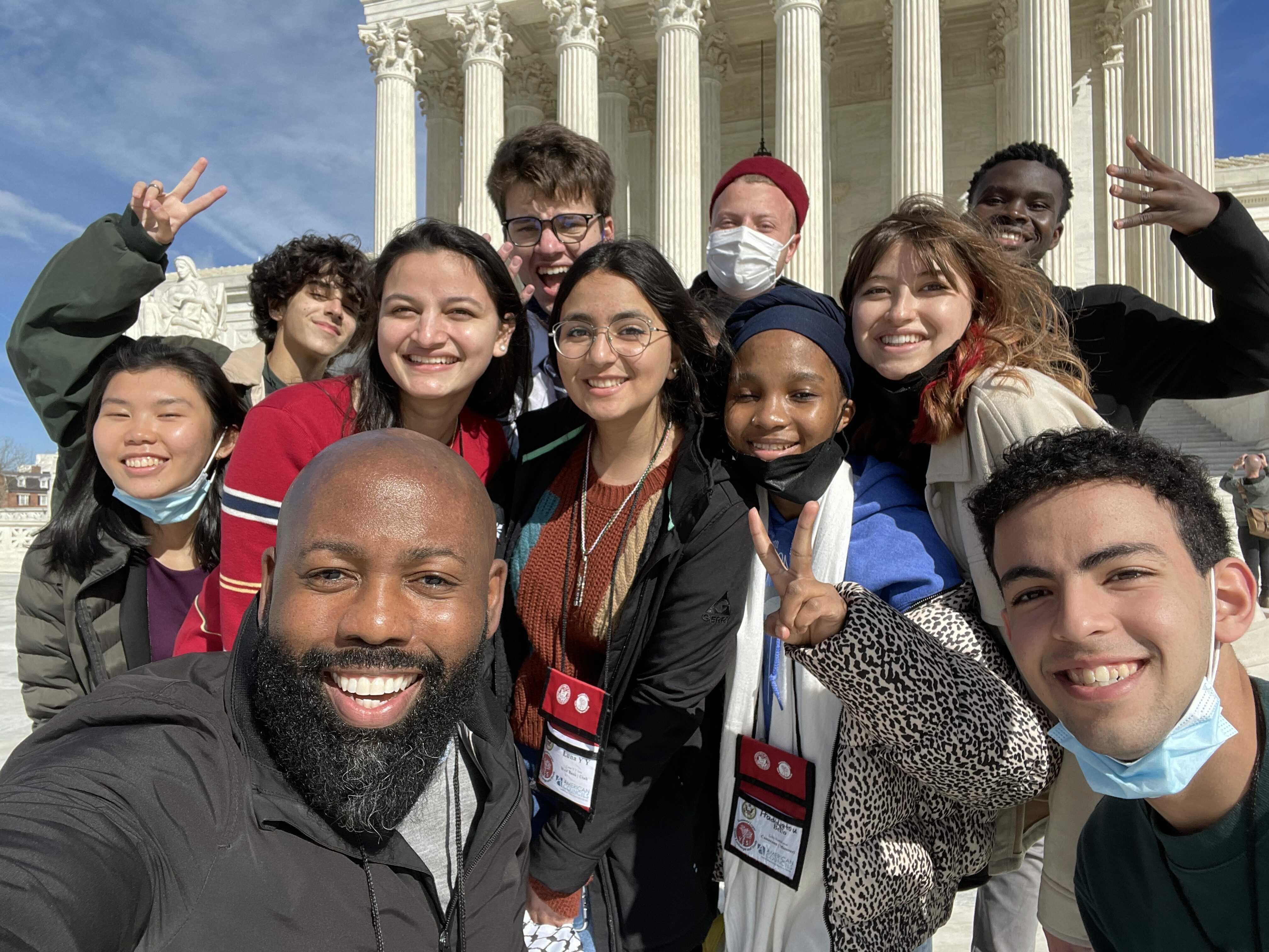 A group of 11 students poses for a selfie outside of a DC memorial