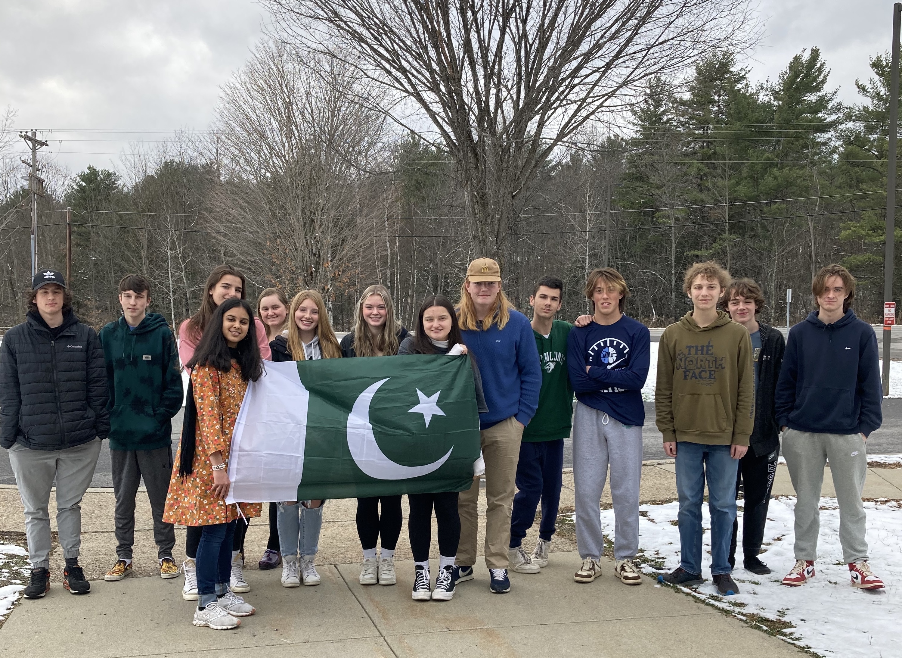 YES student Aleeza standing outside with a group of peers, holding the Pakistani flag.