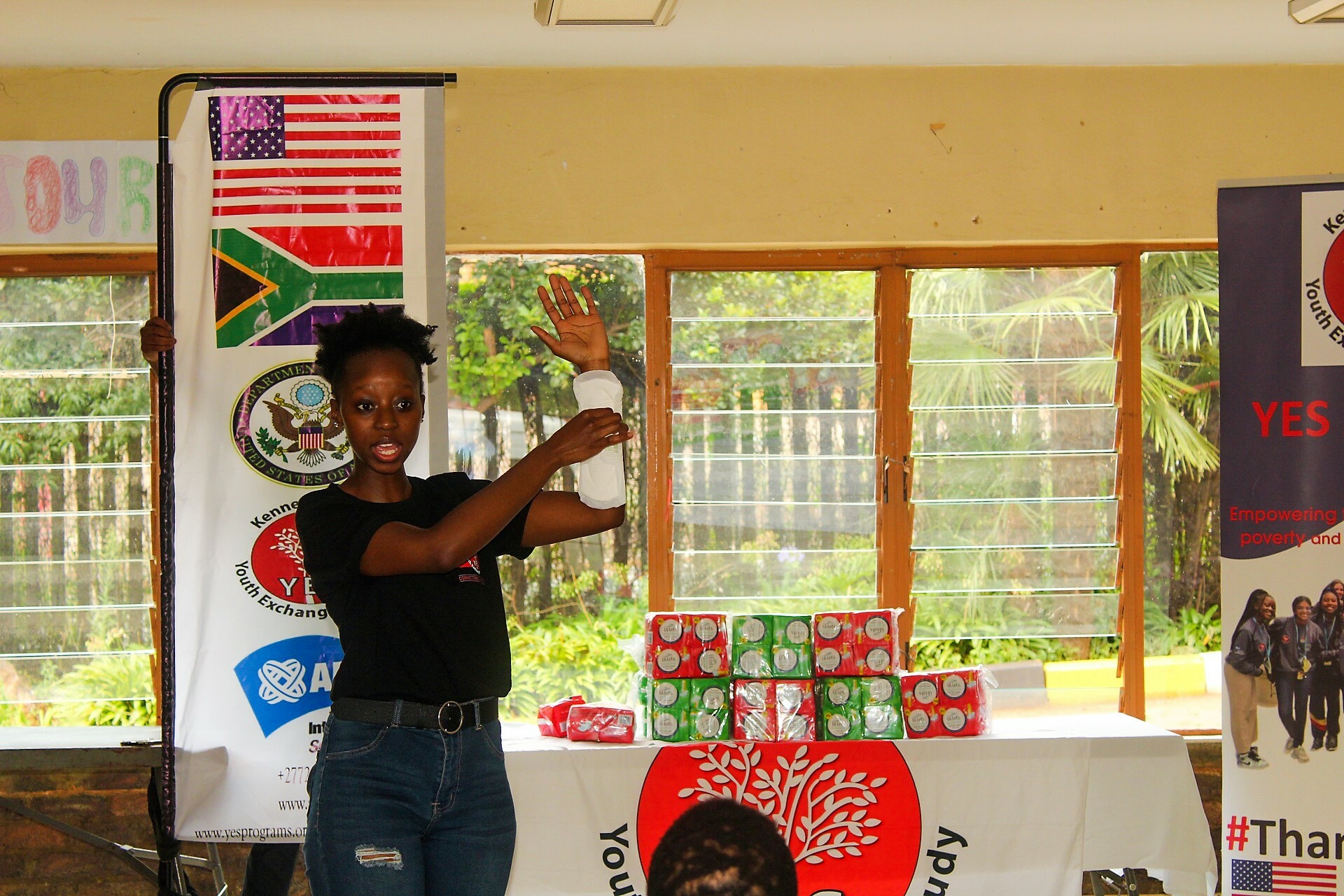 Alumna In South Africa Is Holding Up A Sanitary Pad Talking To A Group Of Young Women About Female Hygiene