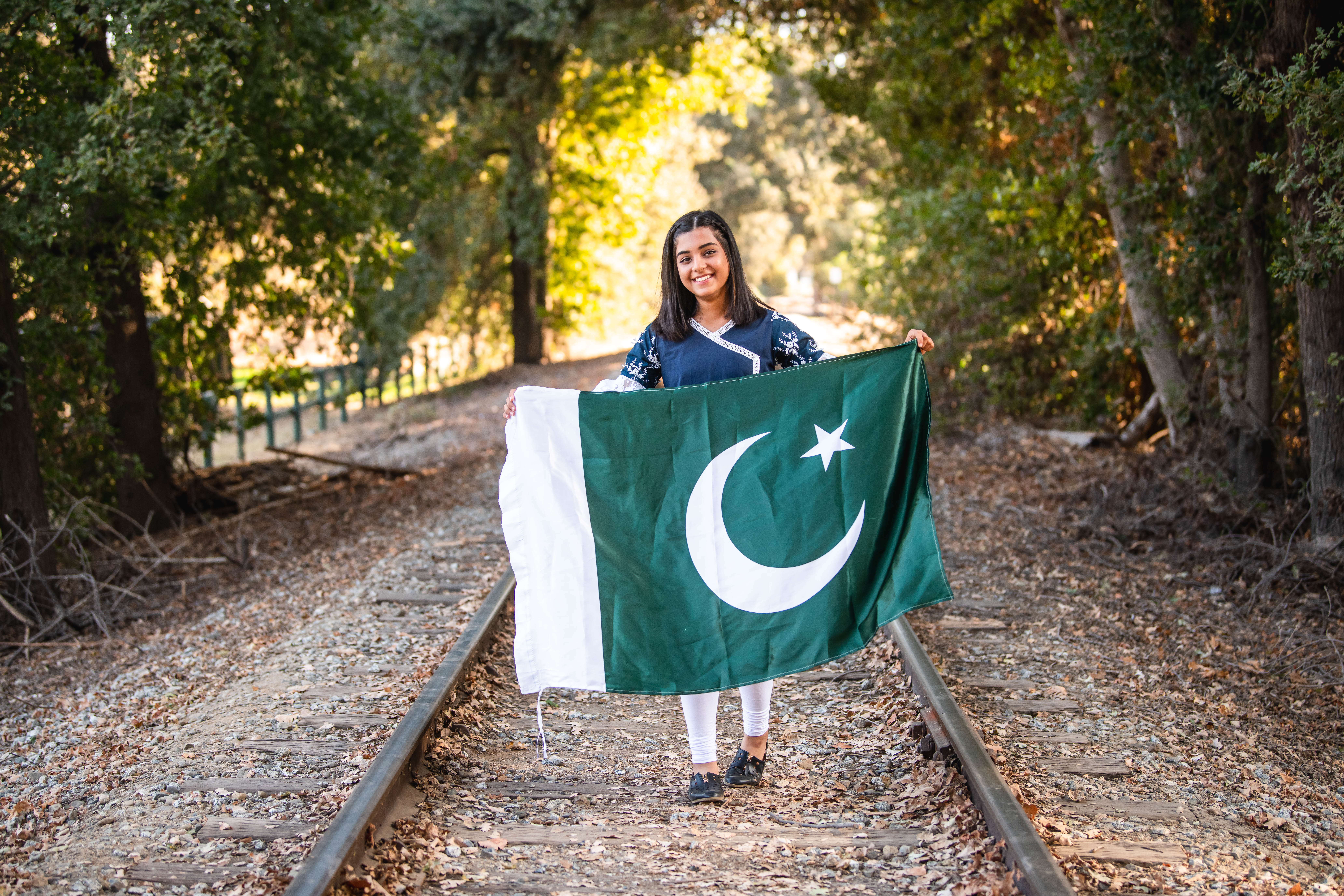 YES student Amna holds a Pakistani flag in the middle of an old railroad track