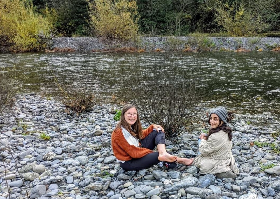 Anamta and friend sit on the rocks near the shoreline of Redwoods Creek