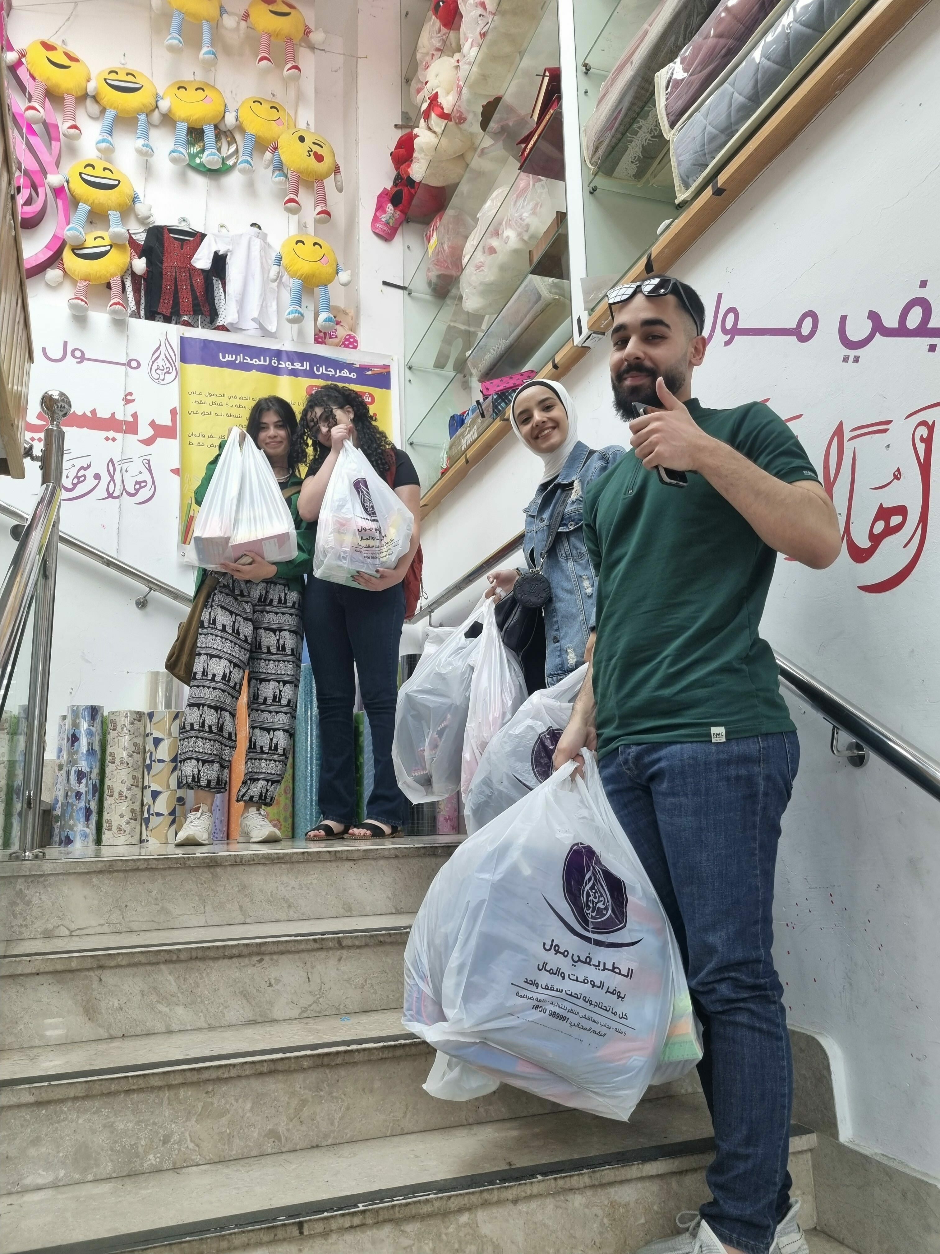 three volunteers pose for a photo with their donations on a staircase