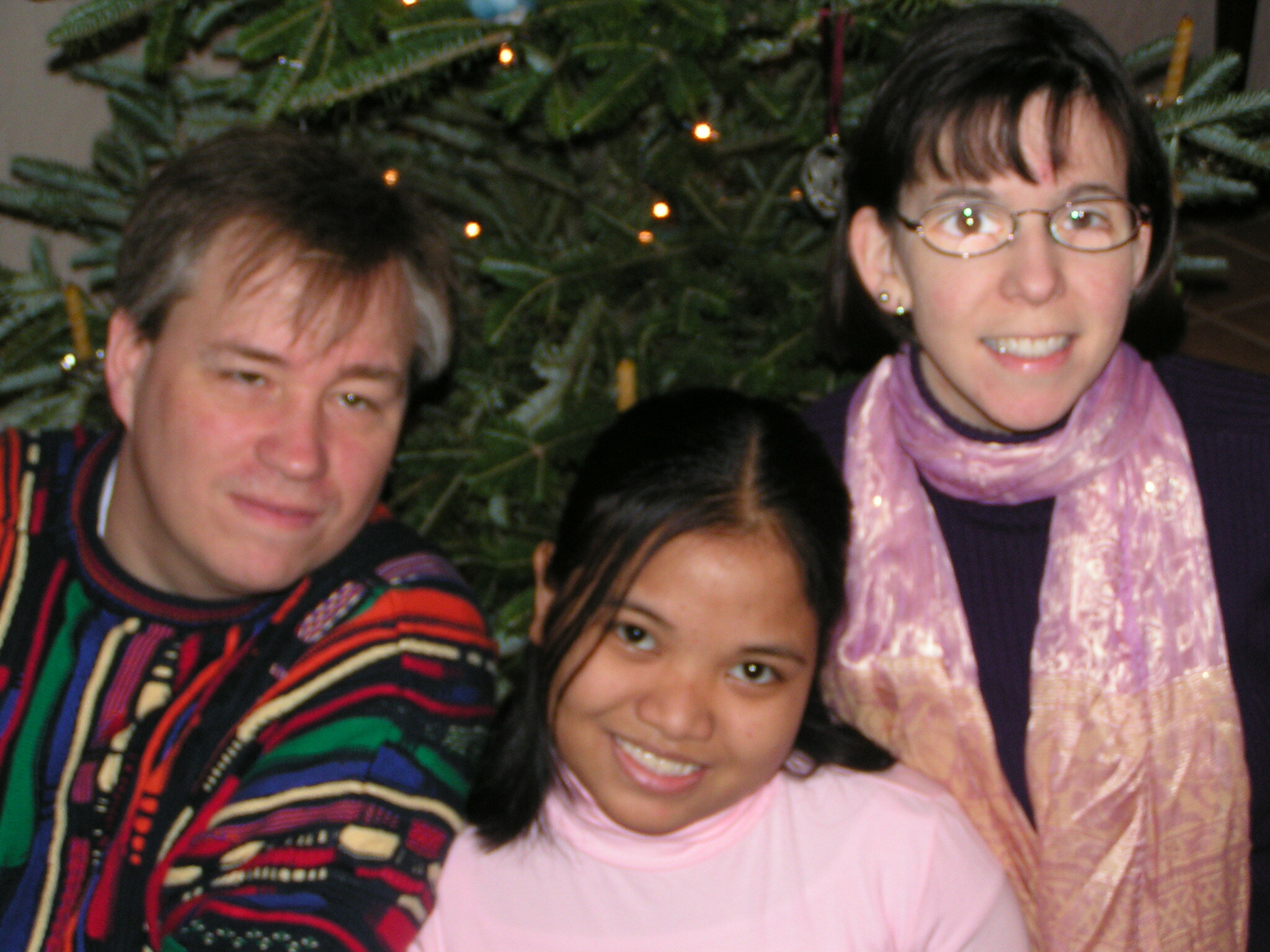 Close Up Photo Of Alumna Posing With Host Parents In Front Of Tree
