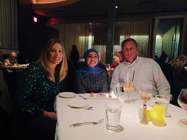 The student and her two host parents pose for a picture at a dinner table