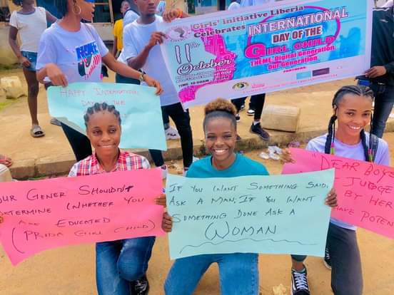 Deborah and other young women hold signs about women empowerment