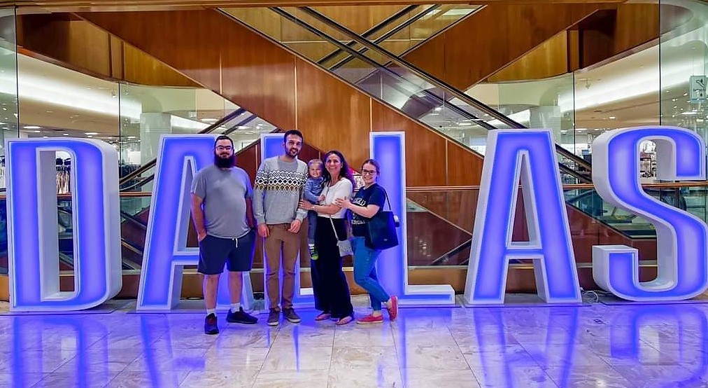 Ugur and host family in front a sign that reads "Dallas"
