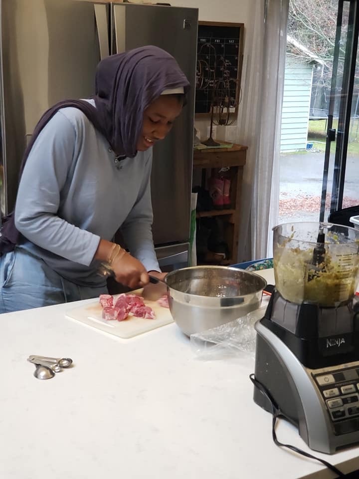 Fatima Chopping Up Meat At A Kitchen Counter