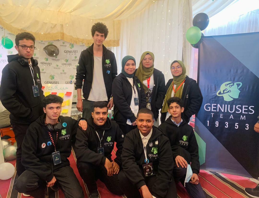 Fatma and her robotics team with the Geniuses team banner