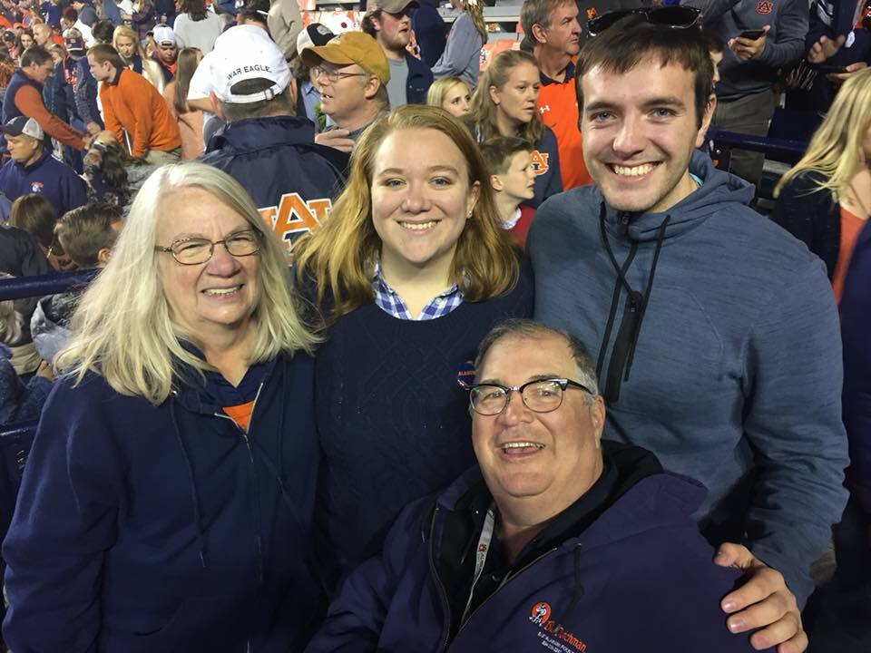 Four People Pose Smiling In A Crowd At A Sports Game
