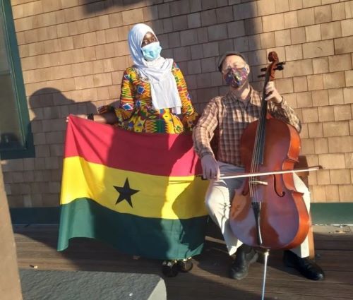 YES student, Samira, holding the Ghanian flag and standing next to someone playing the cello.