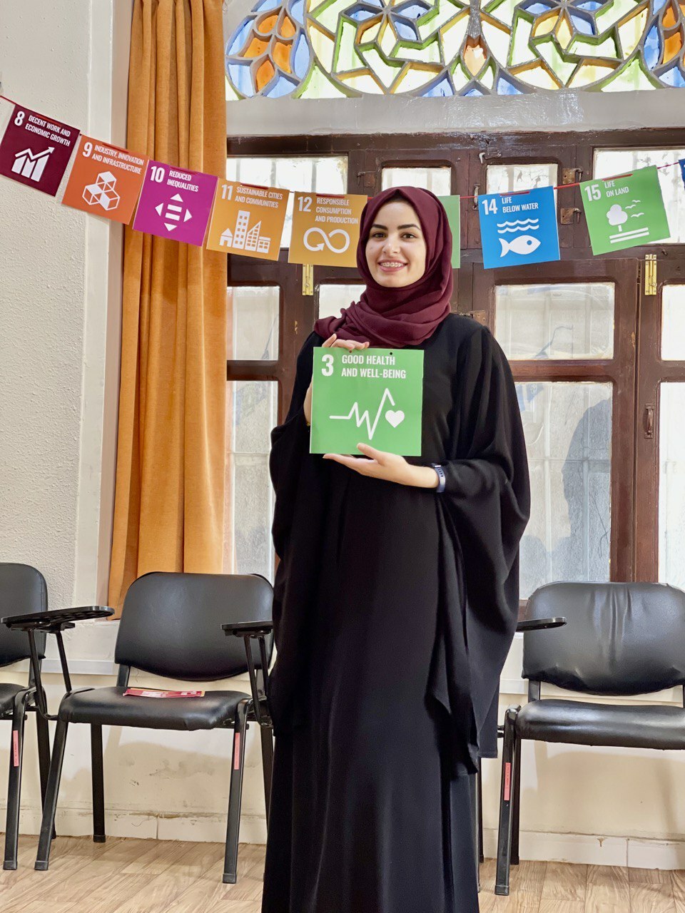 Haya Holding An Sdg Sign In Front Of An Sdg Banner