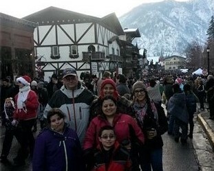Heba and her family pose for a picture in a crowded street in the winter, surrounded by snowy mountains and German style buidings