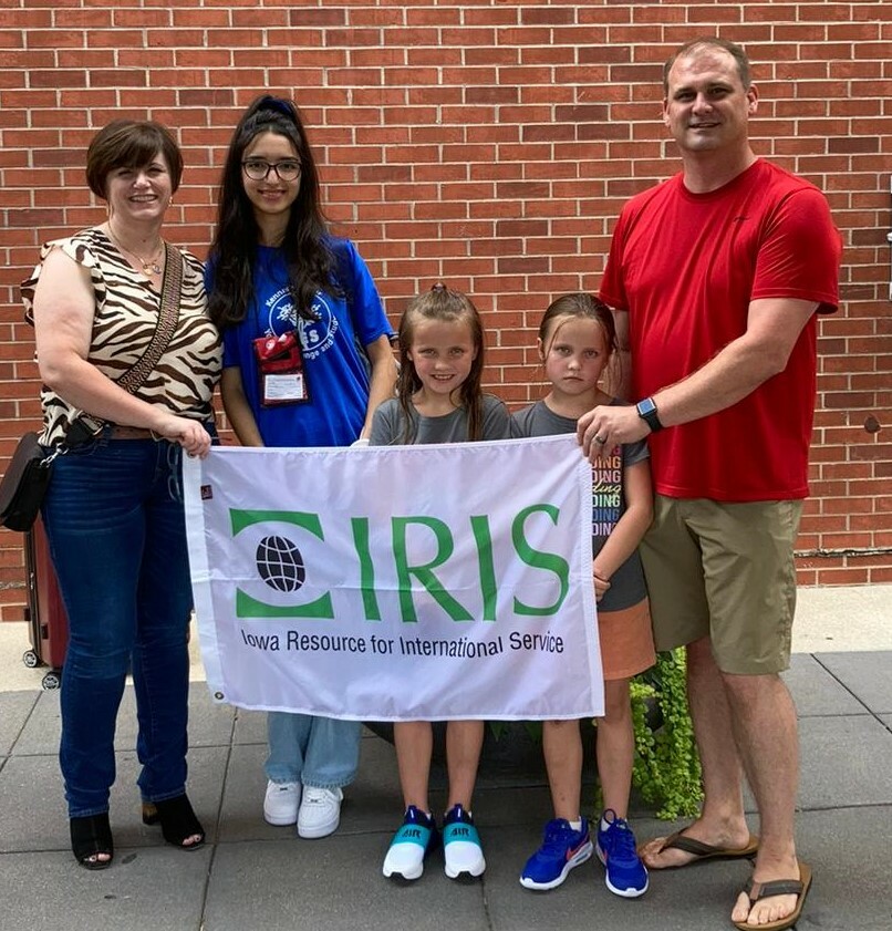 A family of three stands with Hind holding an IRIS flag