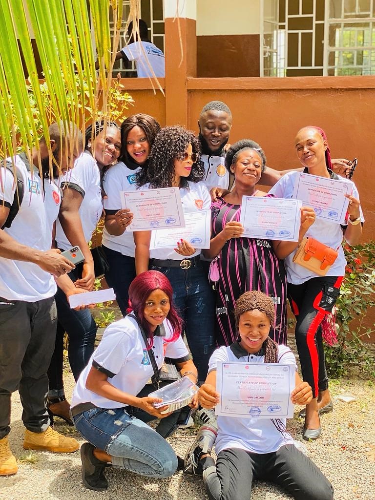 A group of workshop participants hold certificates and smile