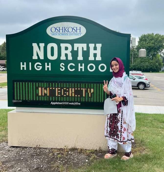 Sahar standing in front of her high school's sign.