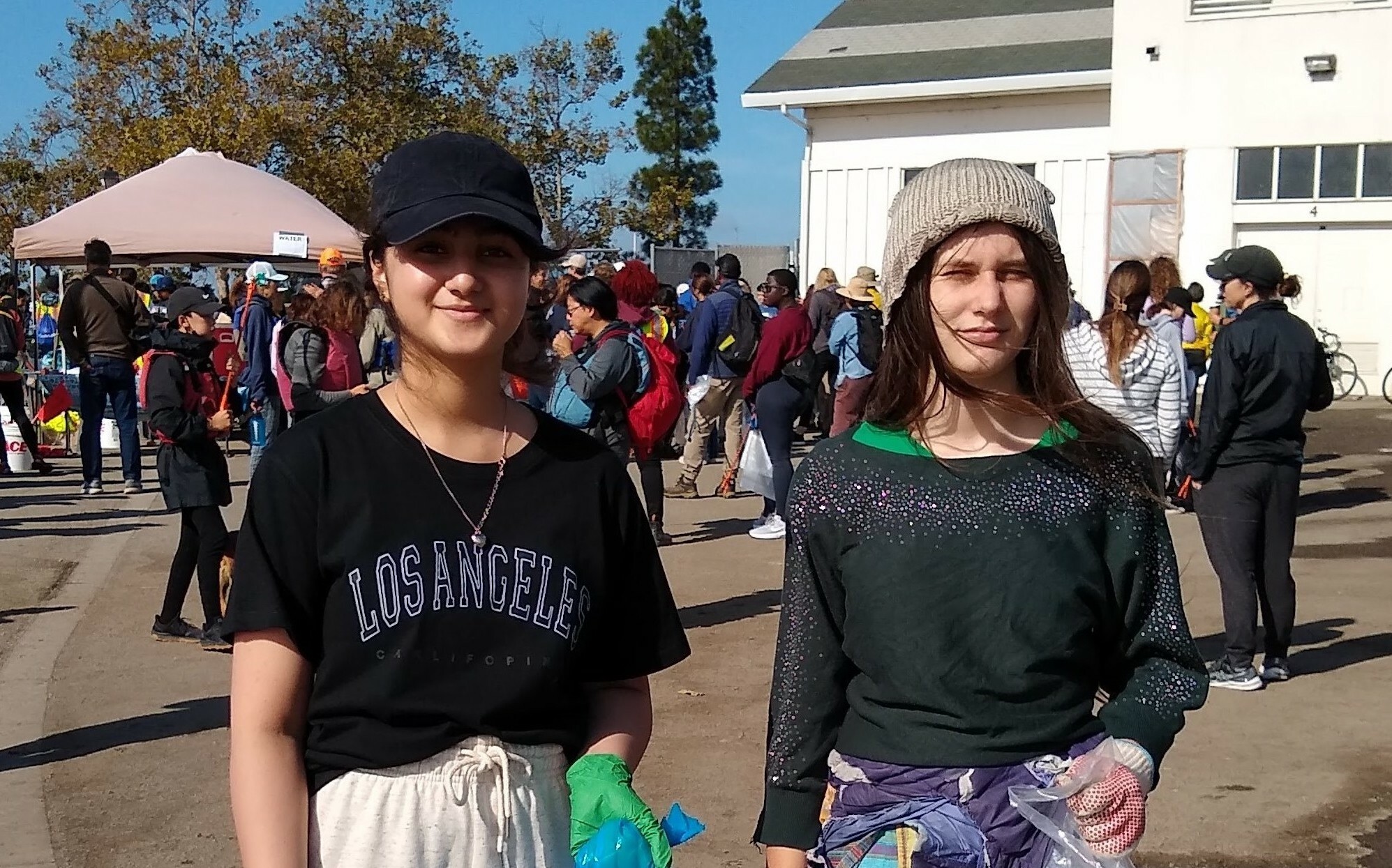 Hina with a friend, holding a trash back at the coastal clean up event.