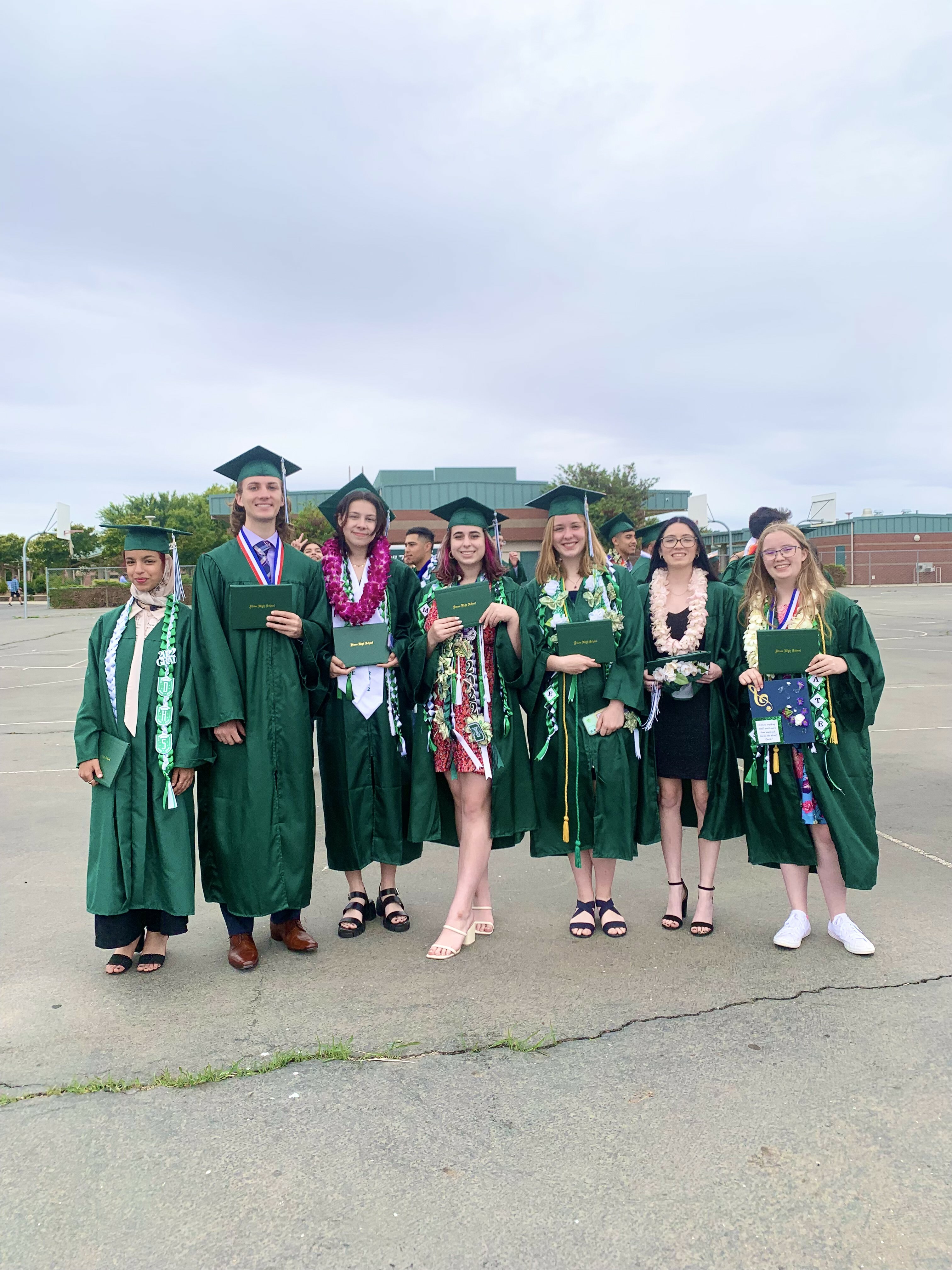 A group of high school students in green graduation regalia