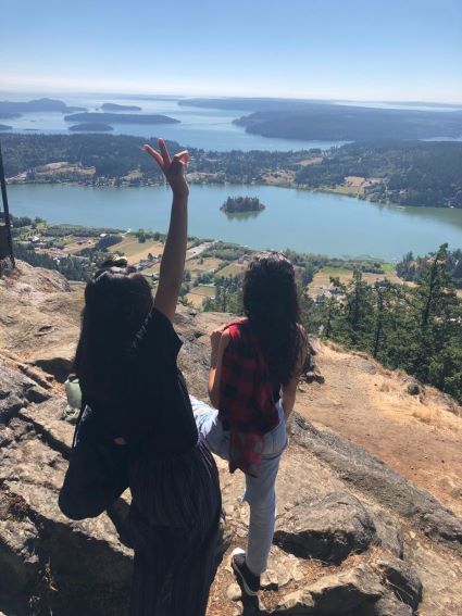 Felicia and her host sister standing on top of a cliff looking over a view of lakes and trees.