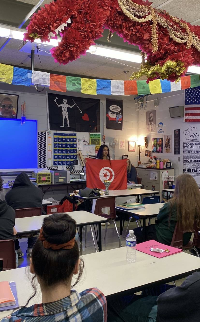 Isra At The Front Of A Classroom Of People Holding The Tunisian Flag