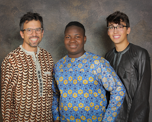 YES student, Jimmy, standing in between his host dad and host brother in traditional Nigerian clothing.