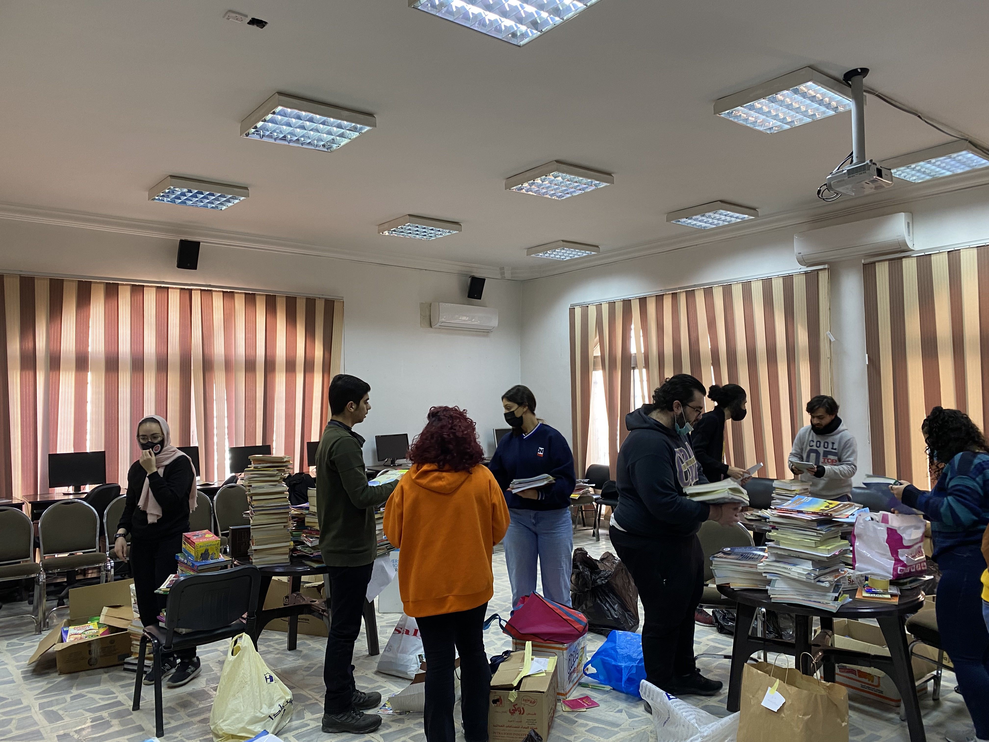 Jordanian YES alumni sorting books in a classroom