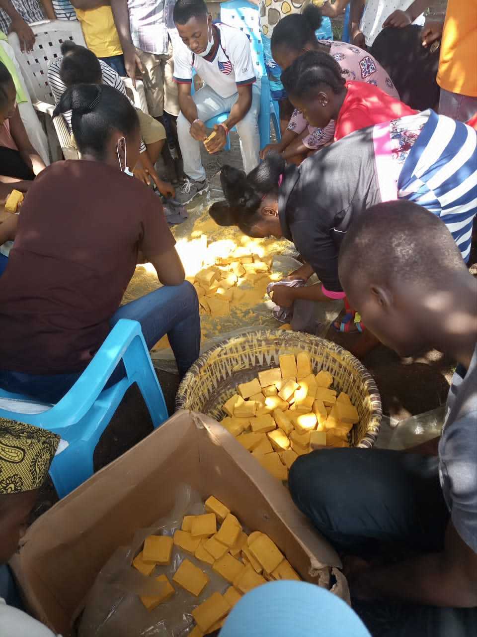 Participants crowding around baskets and buckets of yellow soap.